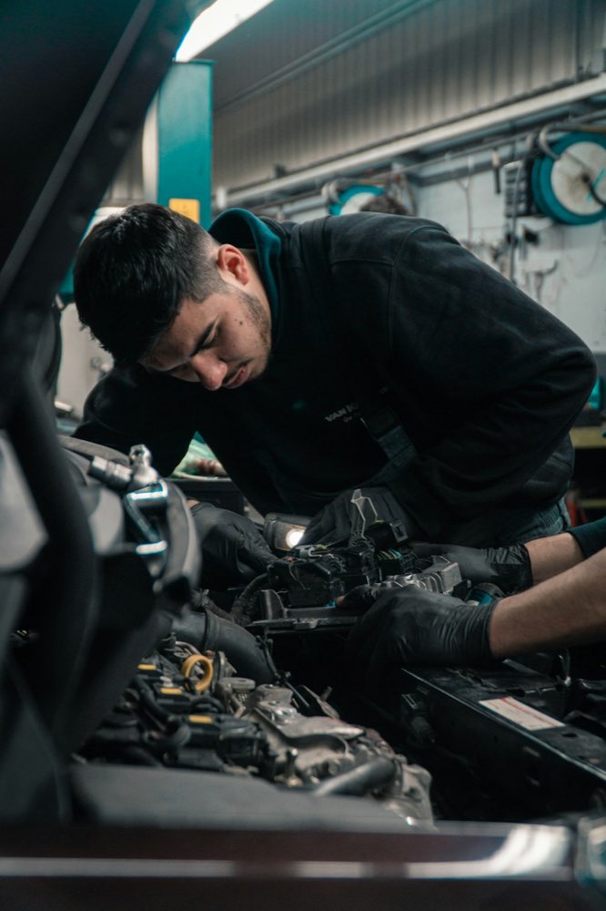 Technician performing an engine repair under the hood