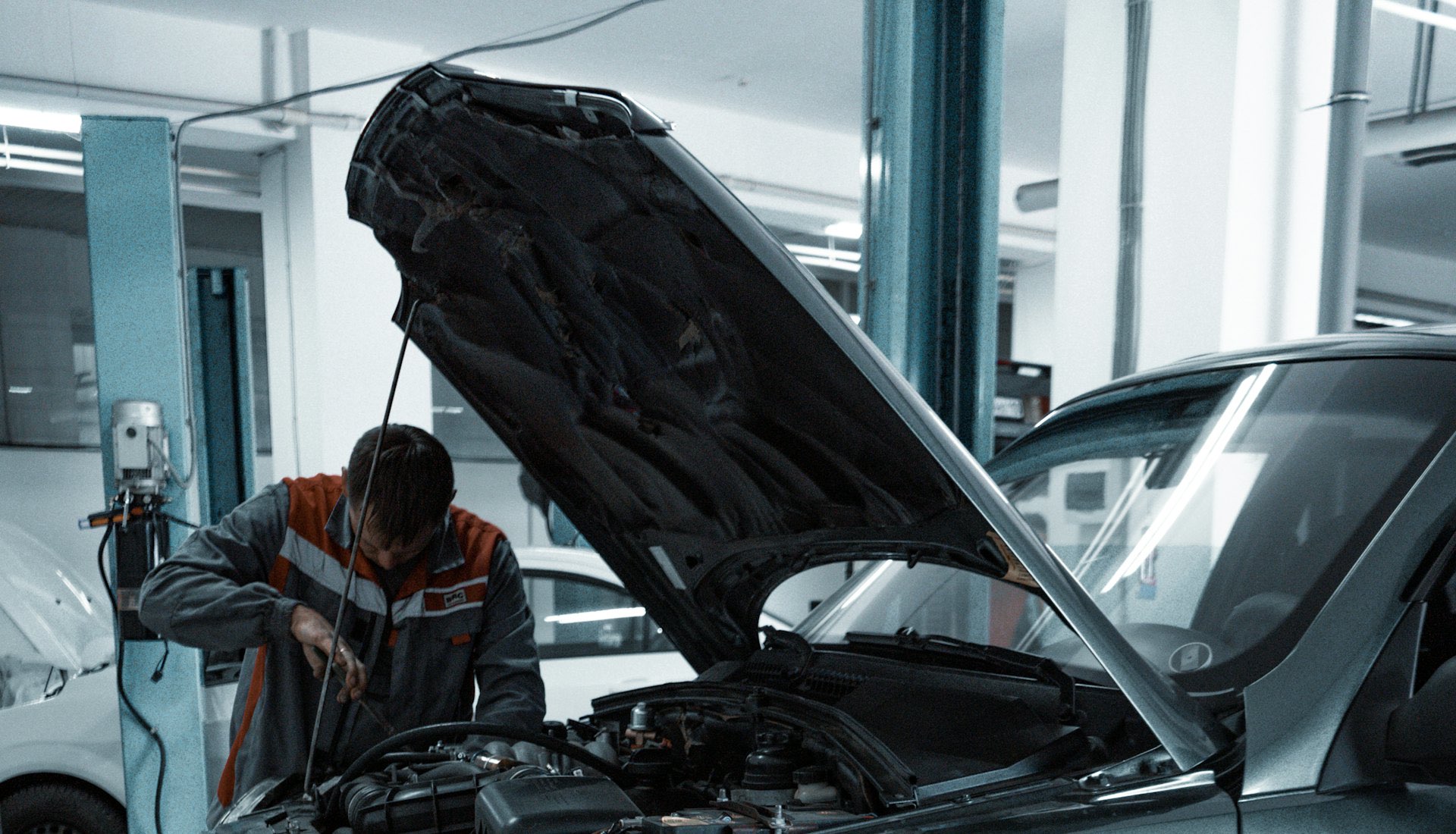 Technician inspecting an engine on a vehicle lift inside a repair bay
